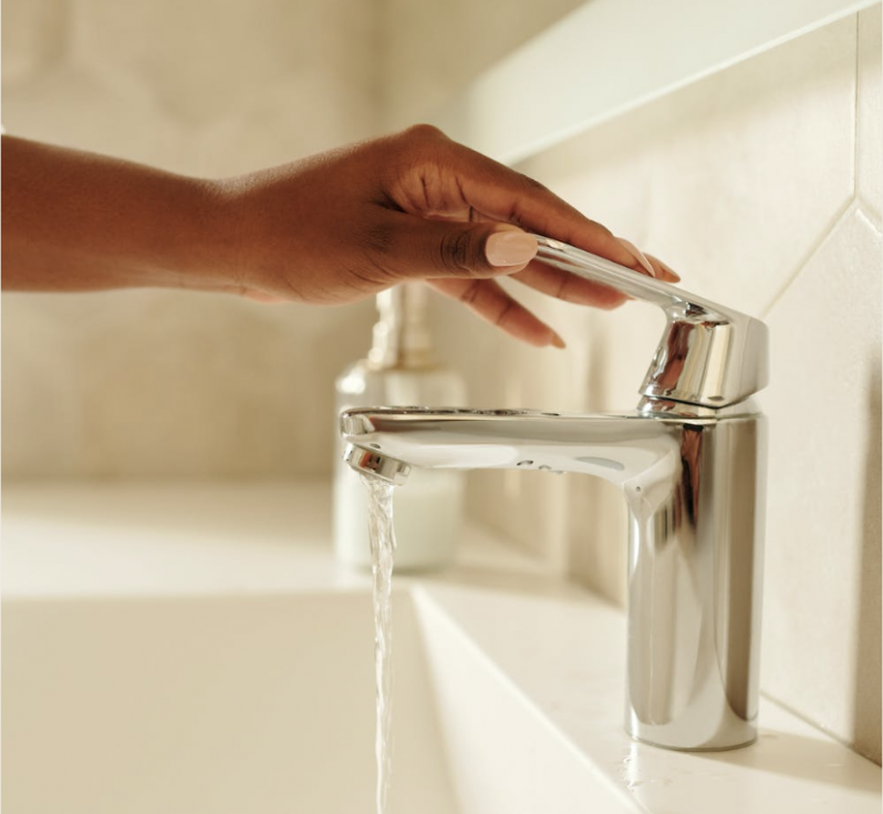 A hand on a running bathroom tap